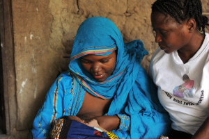 CHANIKA, TANZANIA -  13-11-19  - With the guidance of a COUNSENUTH (Centre for Counselling, Nutrition and Health Care) volunteer, Maimuna Ali breastfeeds her three-week old daughter Jasmine Adam outside her home in Chanika, Tanzania on November 19, 2013. Maimuna, who has five children says she doesn't have any wishes for her children's future jobs. "It doesn't matter -- whatever God wills."  Photo by Daniel Hayduk